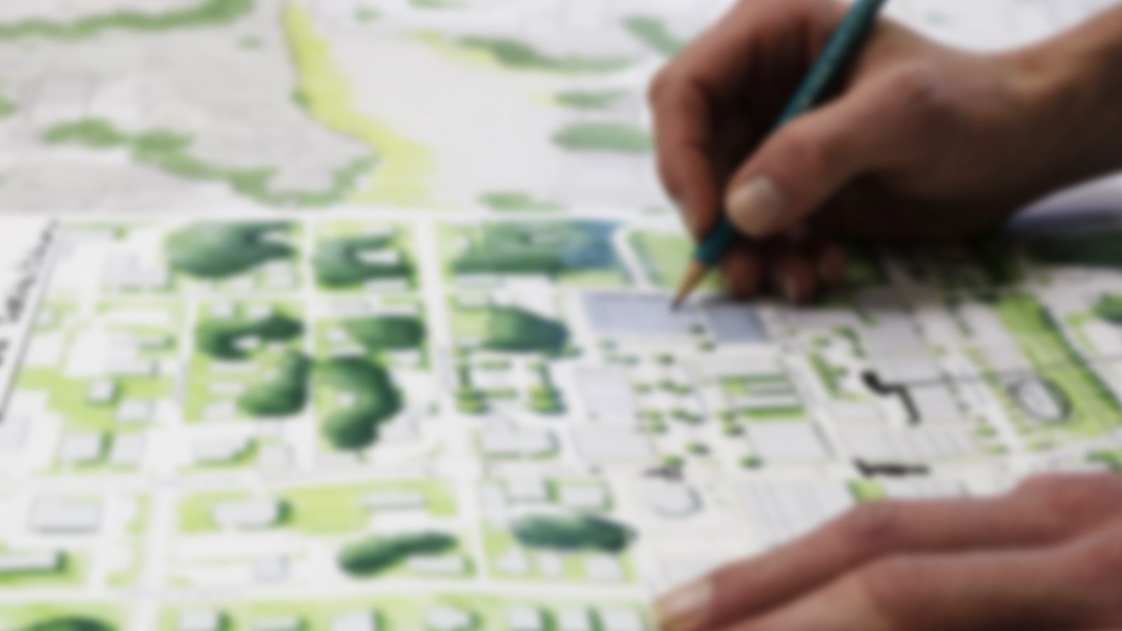 Hands seen holding pencil and drawing a landscape.