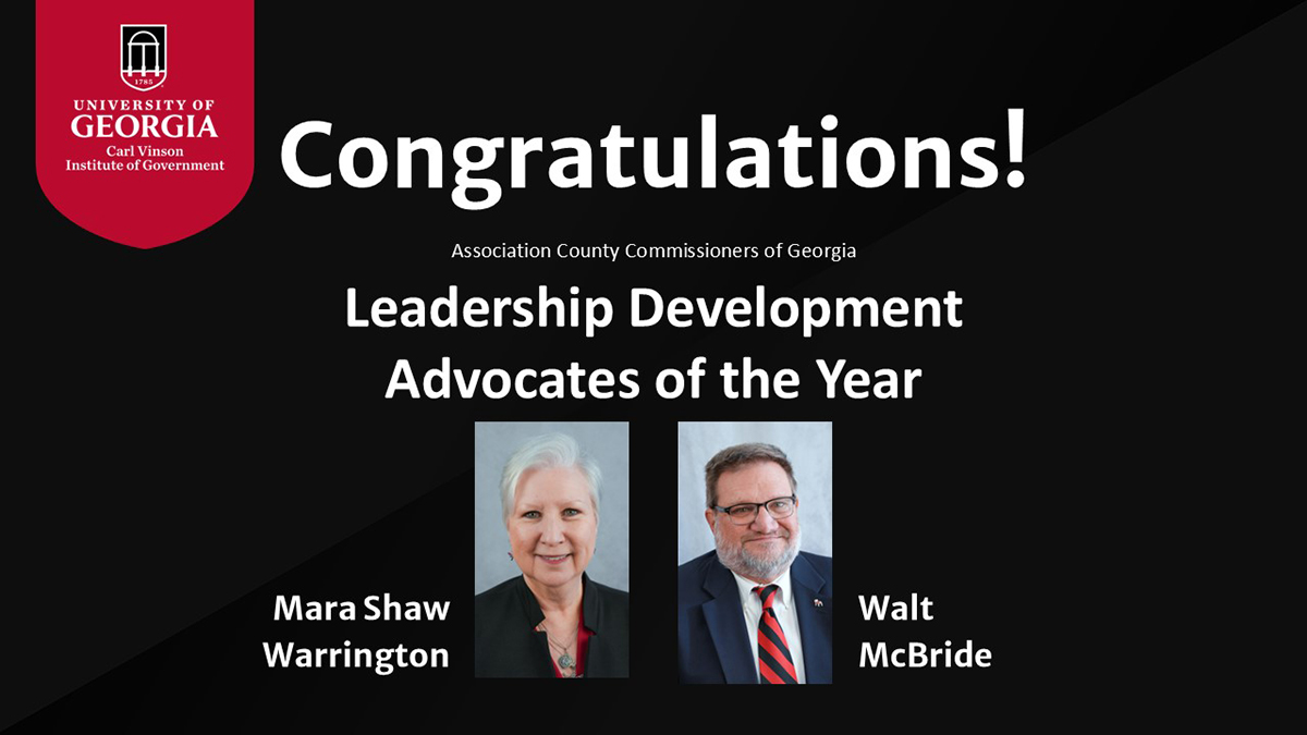 This image says "Congratulations! Association County Commissioners of Georgia Leadership Development Advocates of the Year Mara Shaw Warrington and Walt McBride." The image shows a red banner with the Institute of Government logo on it in the top right corner of the image. The graphic has a black background and displays a picture of Mara Shaw Warrington and Walt McBride.
