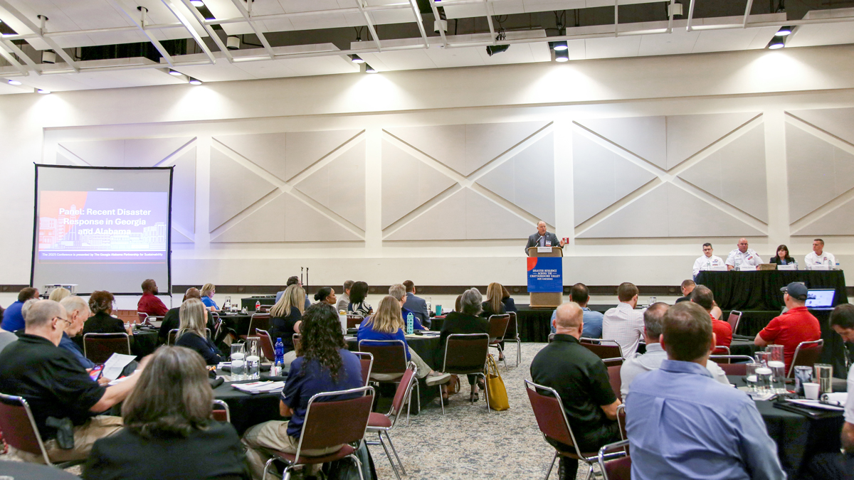 People sitting in a room listening to a speaker give a presentation.